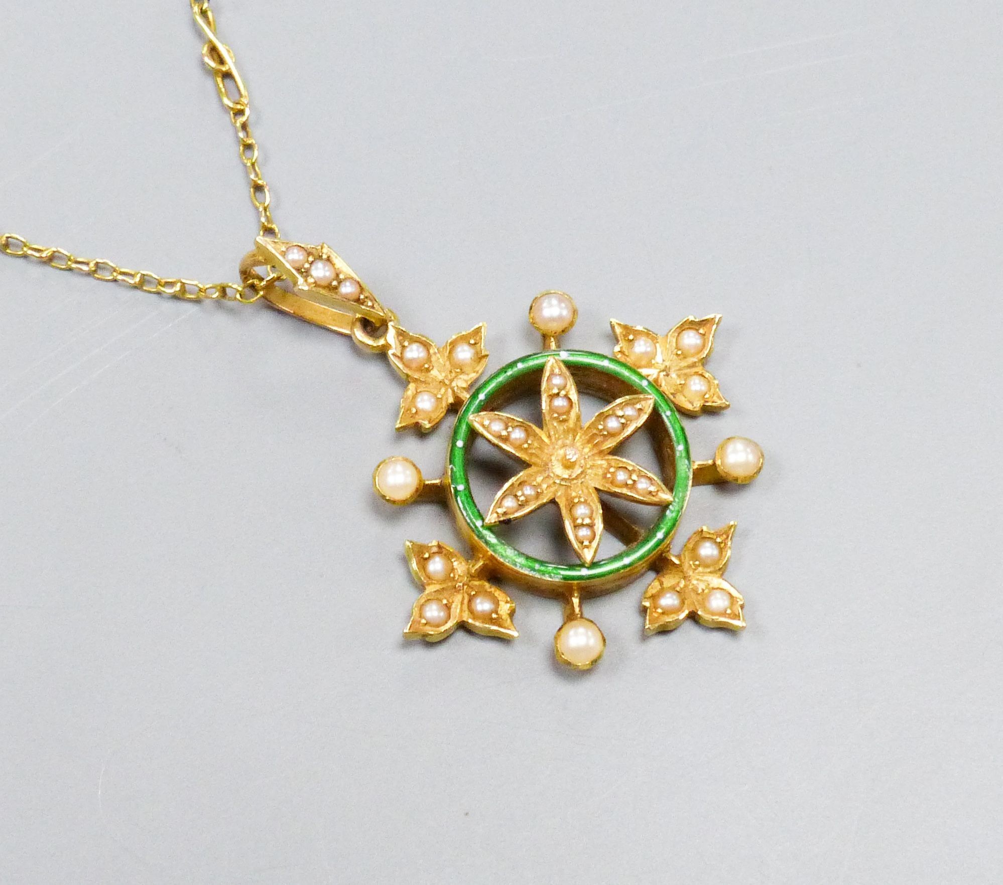 A yellow metal, enamel and split pearl set circular pendant with foliate border, overall 36mm, on a 9ct fine link chain, 40cm, gross weight 7 grams.